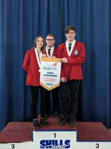 students stand on a podium with a first place award