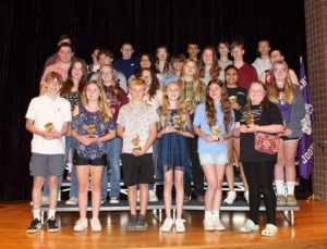 Four rows of students stand with their awards