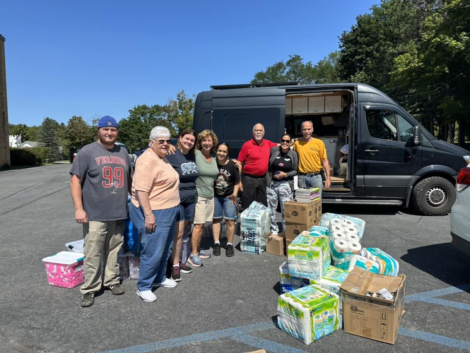 group of people in front of a van with supplies