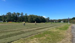open soccer field with crew working, blue sky