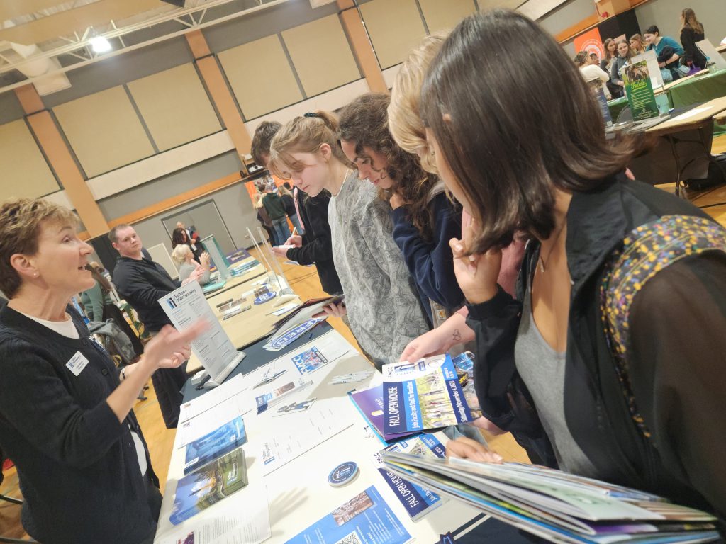 students mingle at a college fair table