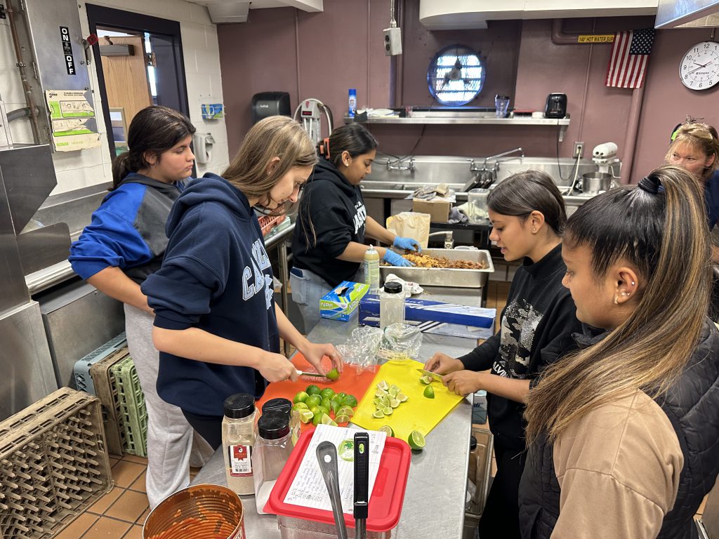 student work together to prepare a school meal in the kitchen