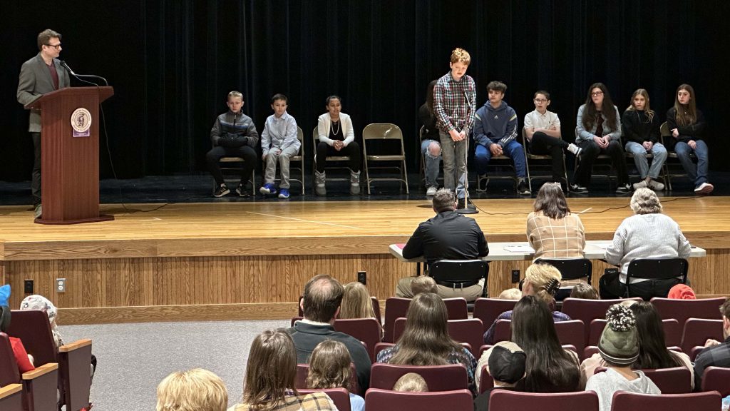 students on stage competing in school spelling bee