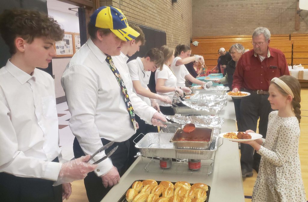 Students serve meals in a line