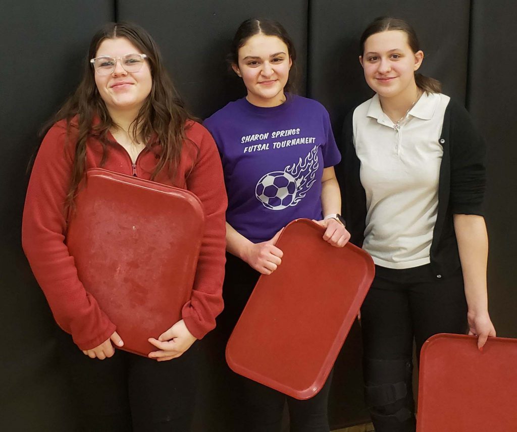 three girls holding cafeteria trays