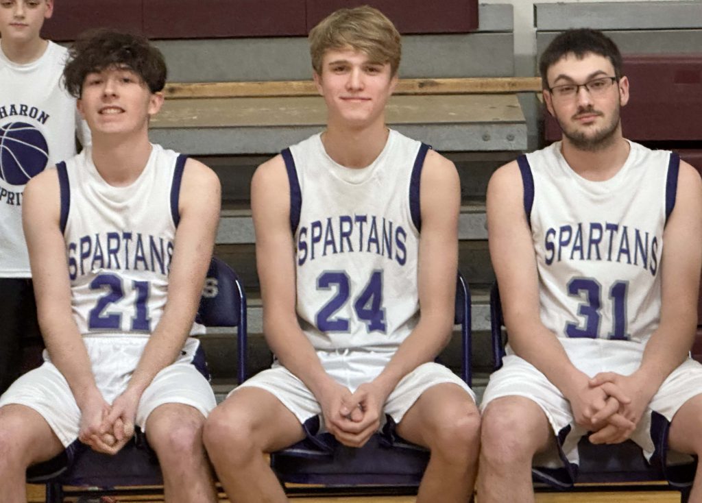 three basketball players sit on the bench