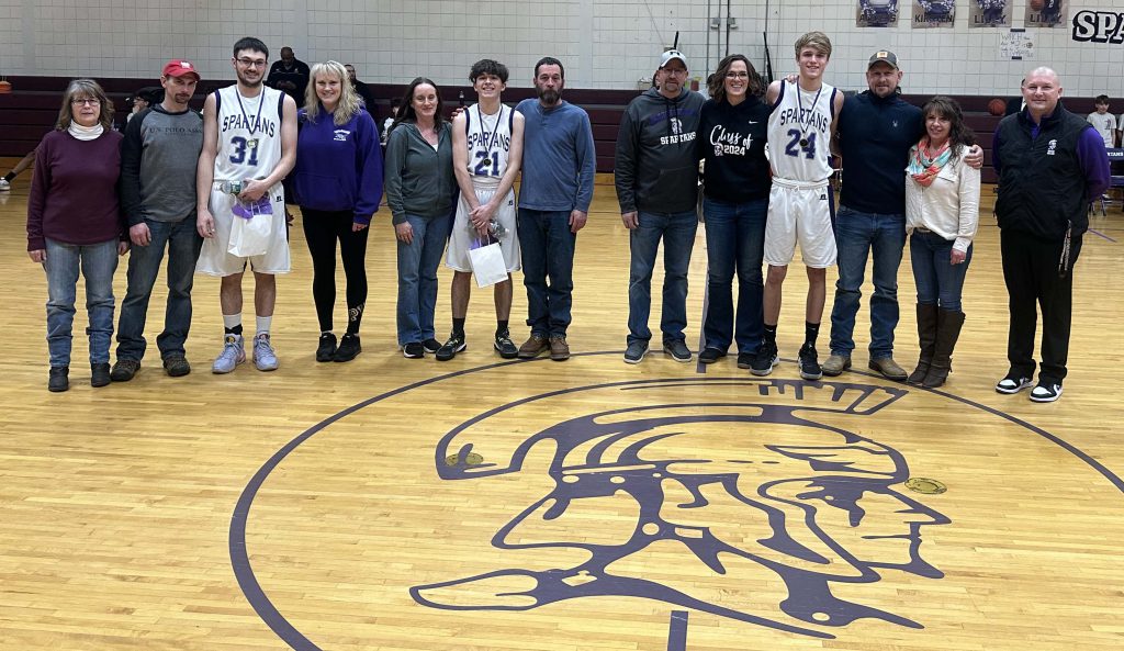 boy basketball players with their families on center court at senior night