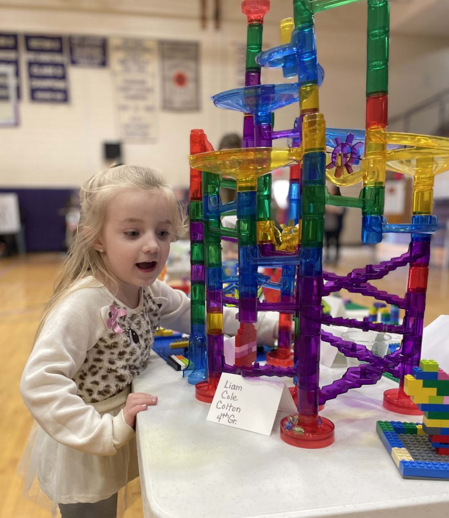 young girl experiments with Lego tower