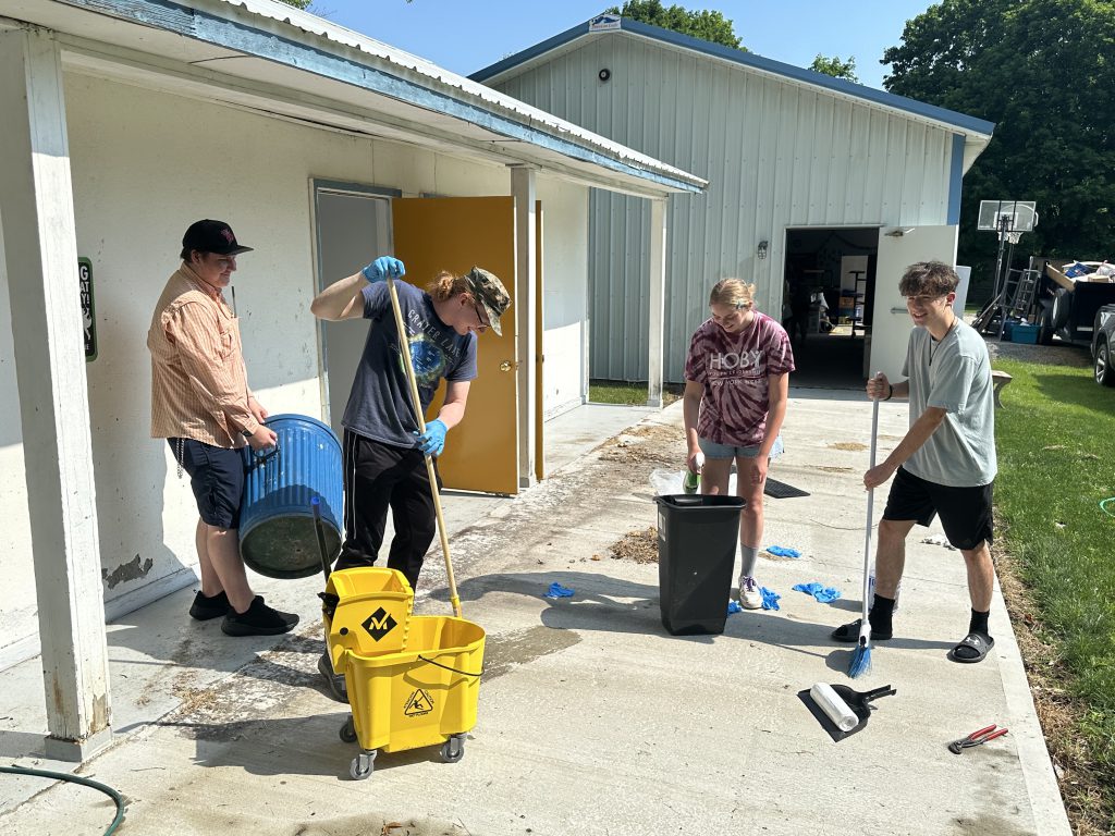 four teens cleaning up a sidewalk