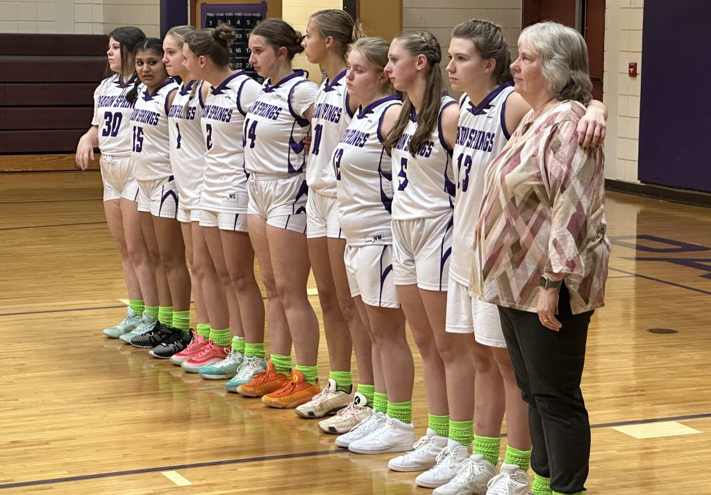 coach stand with her players on the basketball court