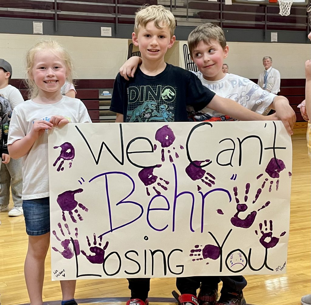 3 kids holding a sign
