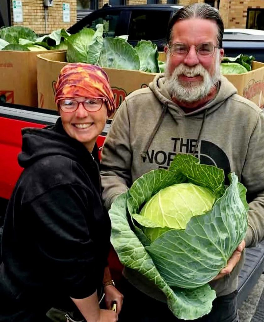 a man and a girl show off a giant cabbage