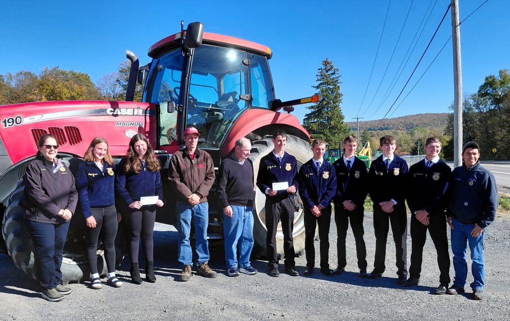 student stand in front of a large farm tractor
