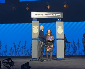 teacher is presented award plaque on large stage