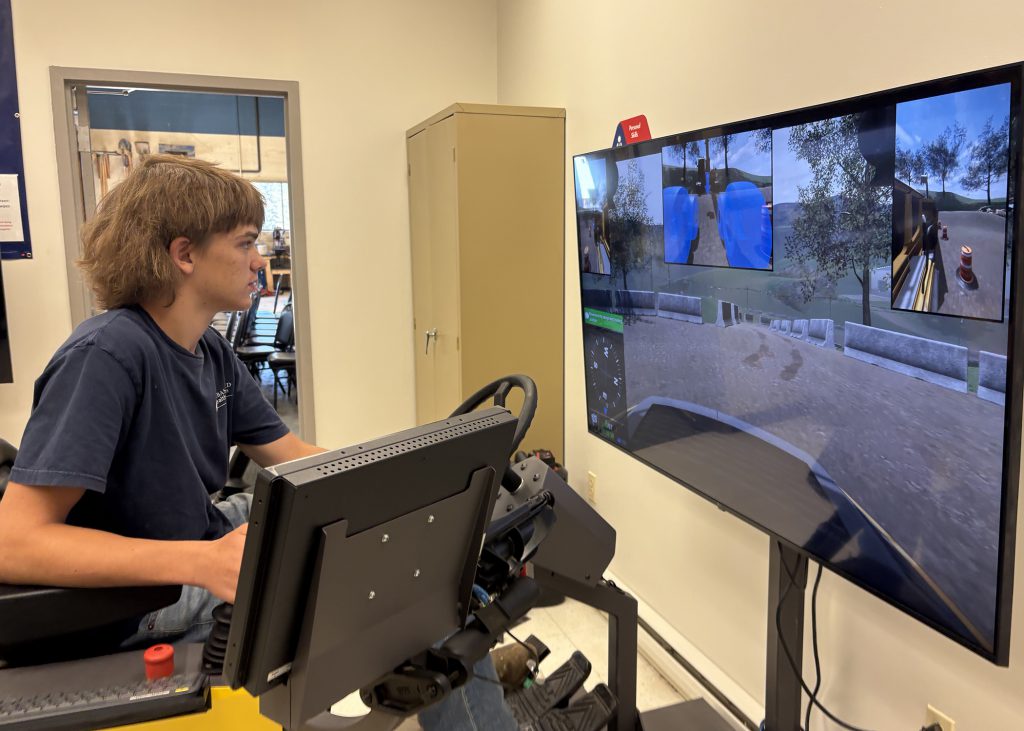 Teen works on simulator to mannuever heaving equipment