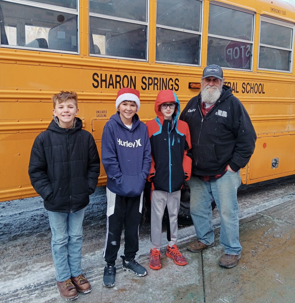 three students and their bus driver outside the school bus