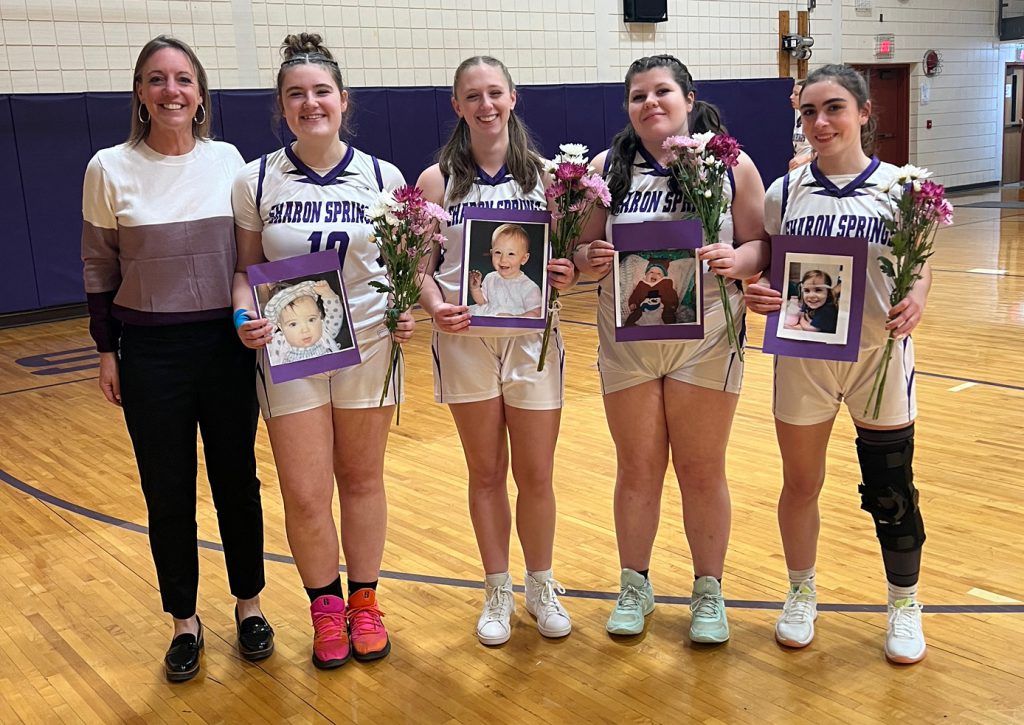 four girl basketball players and their coach on senior night