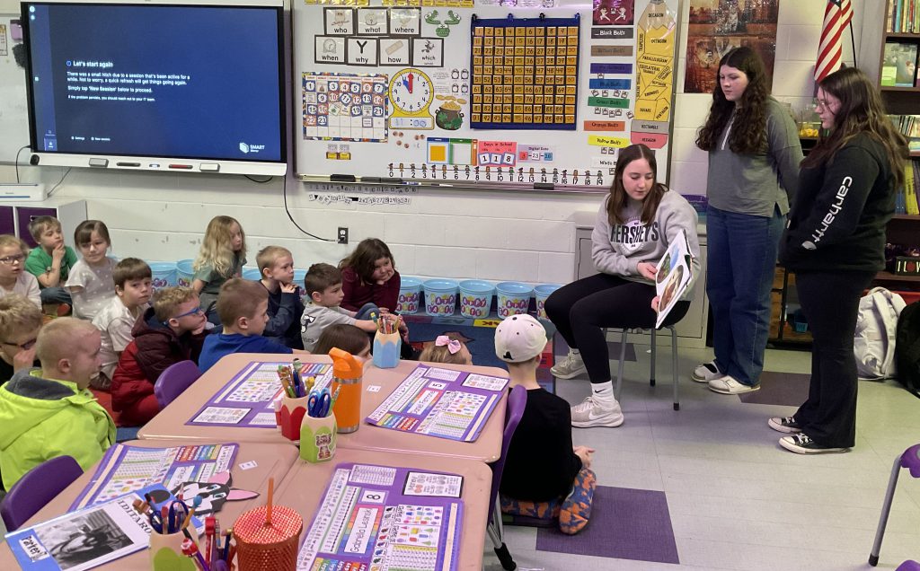 three girls read to the second grade