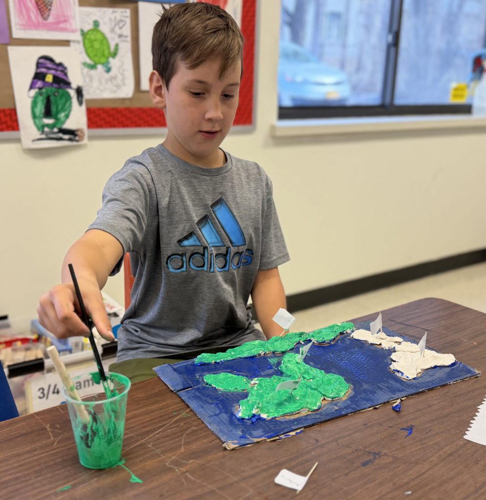 third grader paints a salt dough map of the world