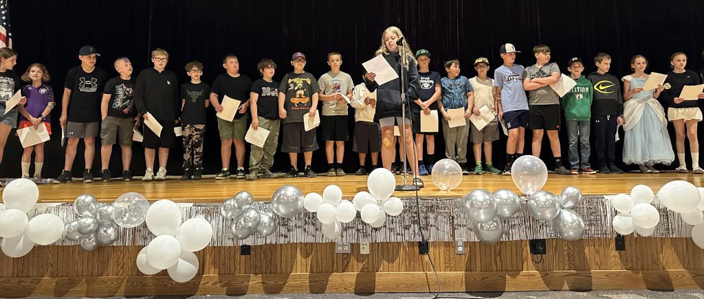 fifth and sixth graders read their family tributes on stage