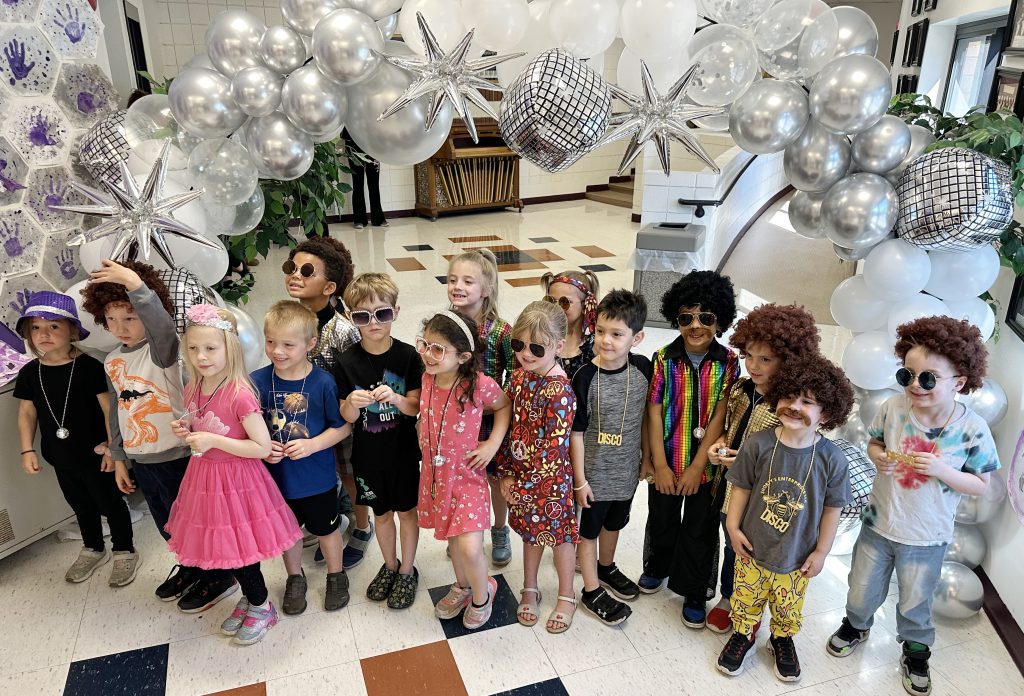 group of kindergarteners dressed in 1970s outfits